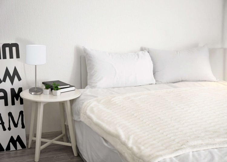 Schlafzimmer mit Bett, Nachttisch und Lampe