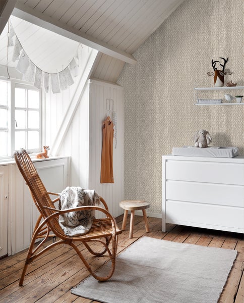 Kinderzimmer mit Wickelkommode, Sessel aus Rattan und gemusterter Tapete