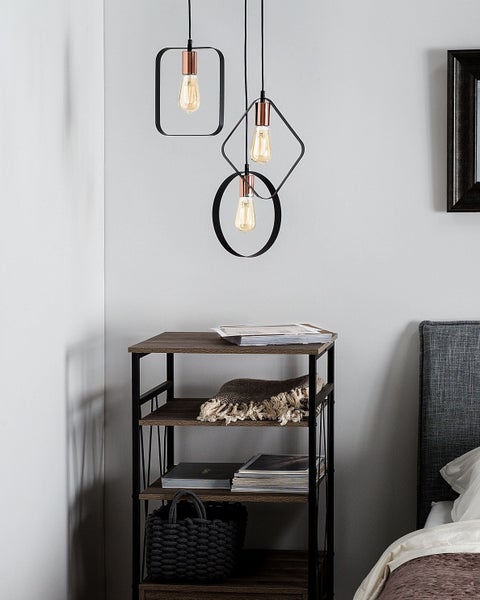 Szene mit einer Hängeleuchte mit geometrischen Formen, einer Holzkommode mit drei Ablagen und einem Teil eines Bettes.