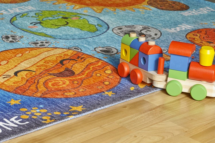Bunter Kinderteppich mit Weltraum-Motiv und Planeten sowie einem Spielzeugzug aus Holz.