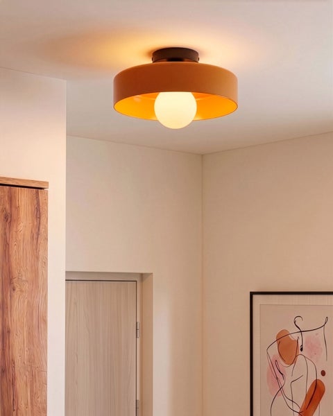 Moderne Deckenleuchte mit orangefarbenem Schirm in einem hellen, minimalistischen Raum mit Holzelementen und abstrakter Kunst.