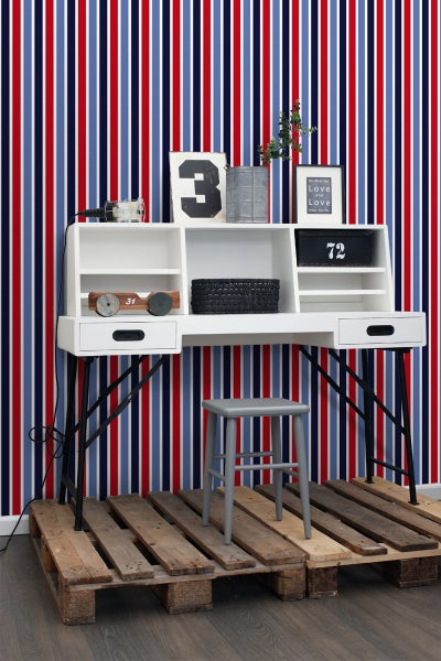 Schreibtisch mit Regalen, Dekoration und Stuhl auf einer Holzpalette vor einer gestreiften Tapete