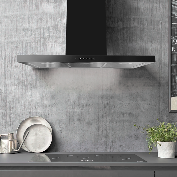 Schwarze Wand-Dunstabzugshaube mit LED-Beleuchtung über einem Induktionskochfeld vor einer grauen Betonwand.