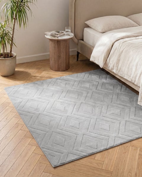 Grauer Teppich mit geometrischem Rautenmuster in modernem Schlafzimmer mit Parkettboden und Bett.