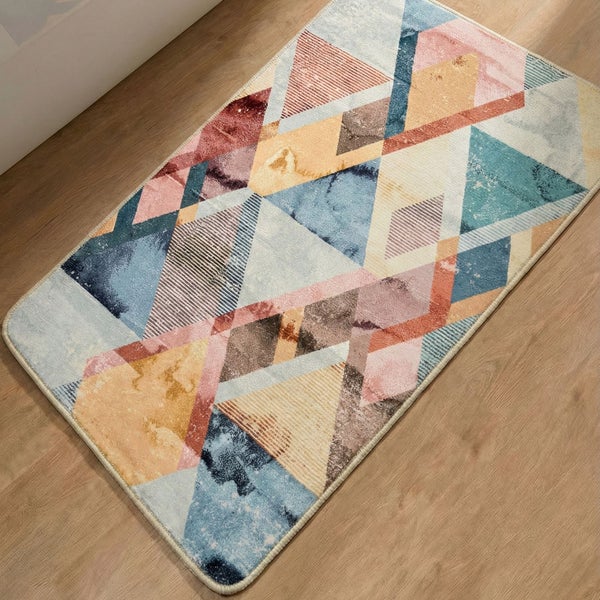 Rechteckiger Teppich mit buntem geometrischem Muster aus Dreiecken und Rauten auf einem Holzboden.