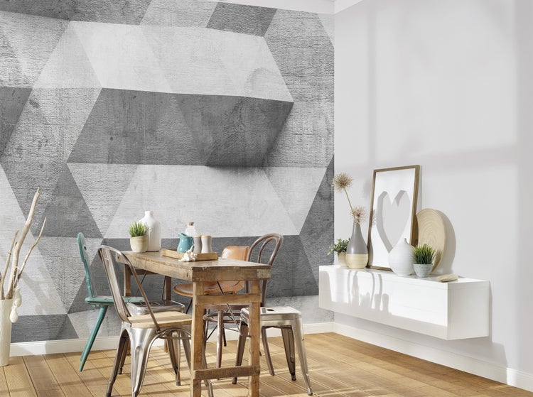 Vliesfototapete mit geometrischem 3D-Muster in Betonoptik in einem modern eingerichteten Esszimmer mit Holztisch und verschiedenen Stühlen.