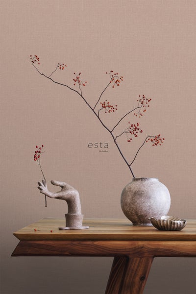 Dekorative Szene mit Blumenvase, Ast mit Beeren und Handskulptur auf einem Holztisch.