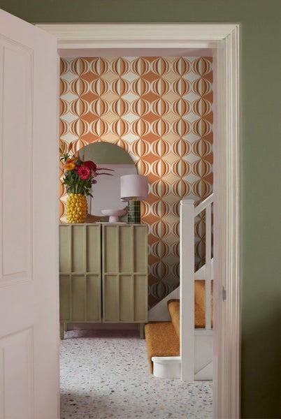 Flur mit Kommode, Spiegel, Lampe, Blumenvase und Tapete mit geometrischem Muster