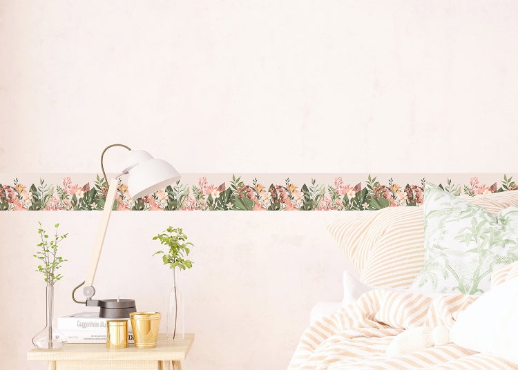 Tapetenbordüre mit Blumenmuster in einem hellen Schlafzimmer über einem Bett und einem Beistelltisch mit Schreibtischlampe.