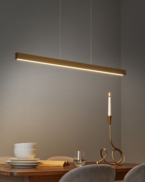 Moderne Esszimmerszene mit LED-Pendelleuchte, Geschirr und Kerzenständer auf einem Holztisch