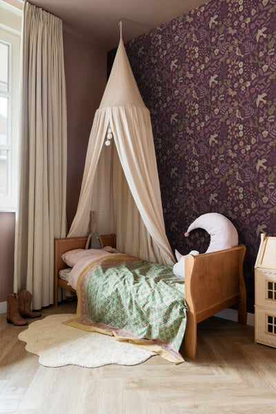 Kinderzimmer mit Himmelbett, gemusterter Tapete und Holzspielhaus