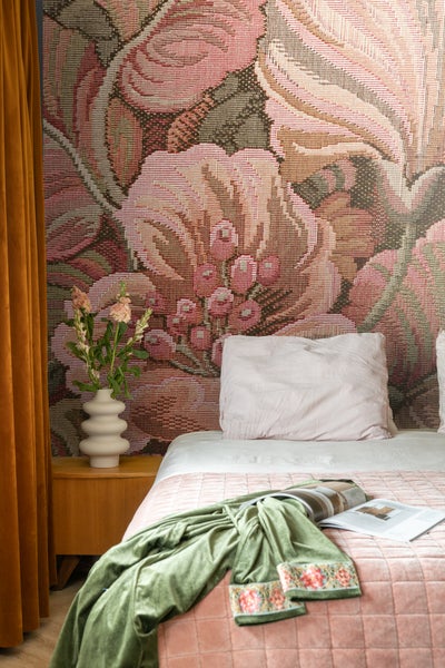 Gemütliches Schlafzimmer mit Blumendesign-Tapete, Nachttisch und Textilien