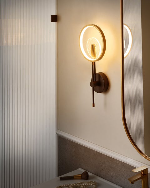 Ein Badezimmer mit einer runden Wandleuchte, einem Spiegel und einem Waschbecken.