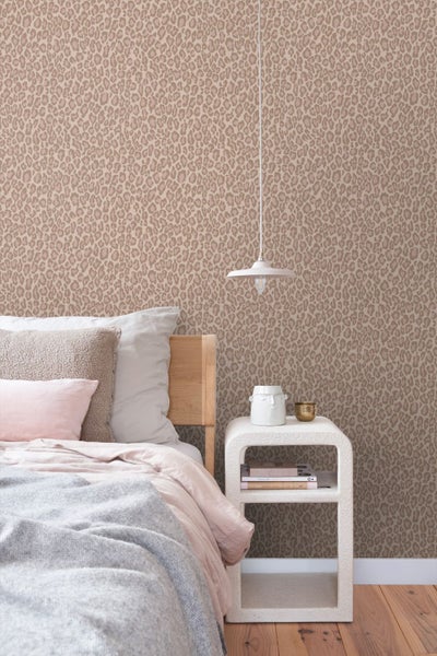 Vliestapete mit Leopardenmuster in einem hellen Kinderzimmer, ein Kind sitzt an einem Schreibtisch vor der gemusterten Wand.