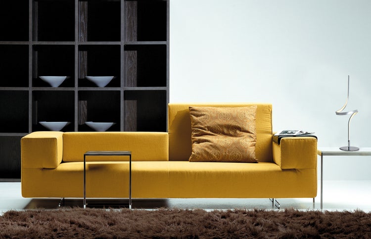Gelbes Sofa mit Kissen, Beistelltisch, Stehlampe und Regal im Wohnzimmer
