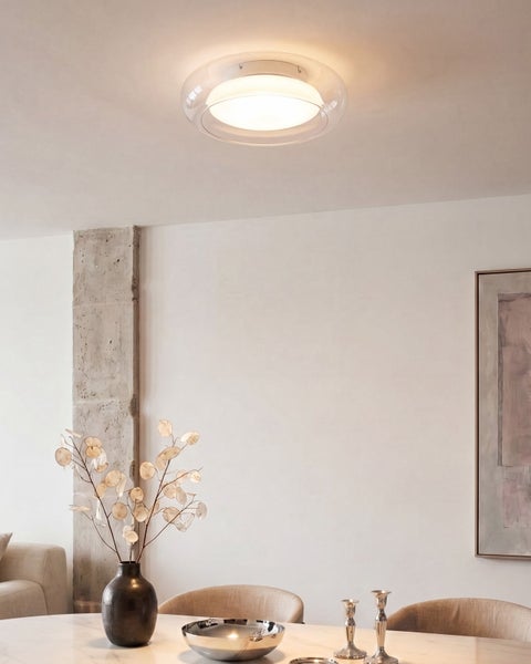 Moderne Deckenleuchte in rundem Design beleuchtet einen elegant eingerichteten Wohnbereich mit Esstisch und Betonsäule.