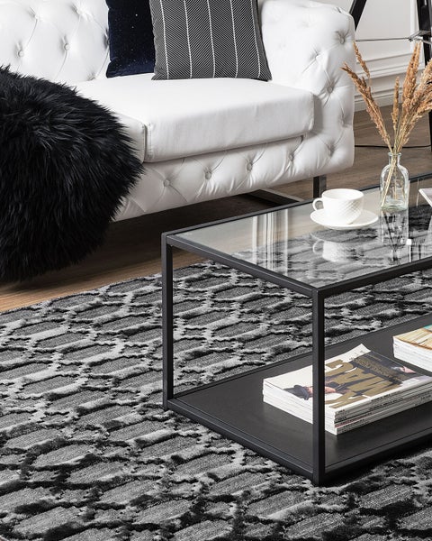 Wohnzimmer mit weißem Sofa, Couchtisch mit Glasplatte und grauem Teppich