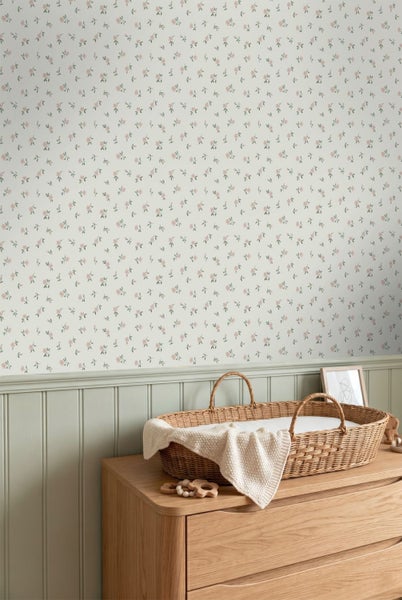Vliestapete mit feinem Blumenmuster in einem Kinderzimmer über einer Wandpaneele mit Wickelkorb auf einer Holzkommode.