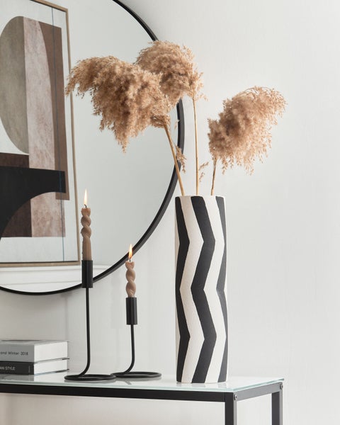 Dekorative Szene mit Vase, Trockenblumen, Kerzen und Spiegel auf einem Tisch