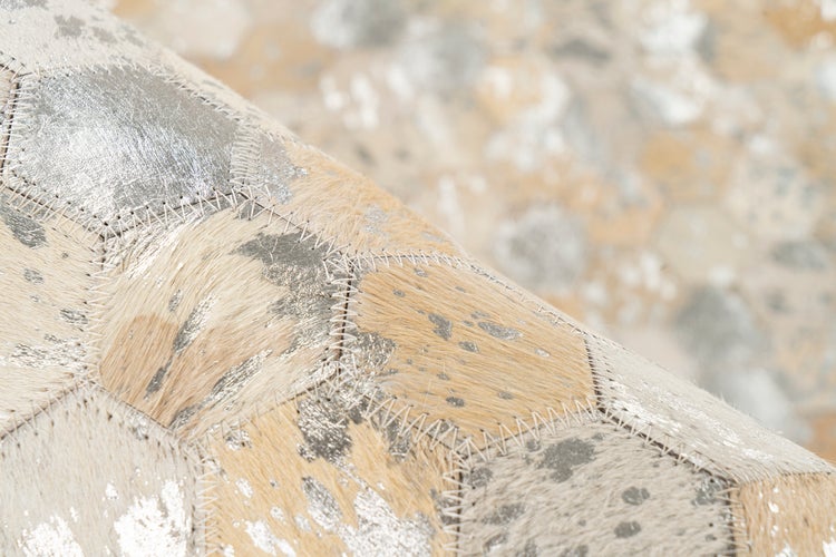 Patchwork-Teppich aus echtem Rinderfell mit sechseckigen Segmenten, Zickzack-Nähten und silbernen Metallic-Akzenten.
