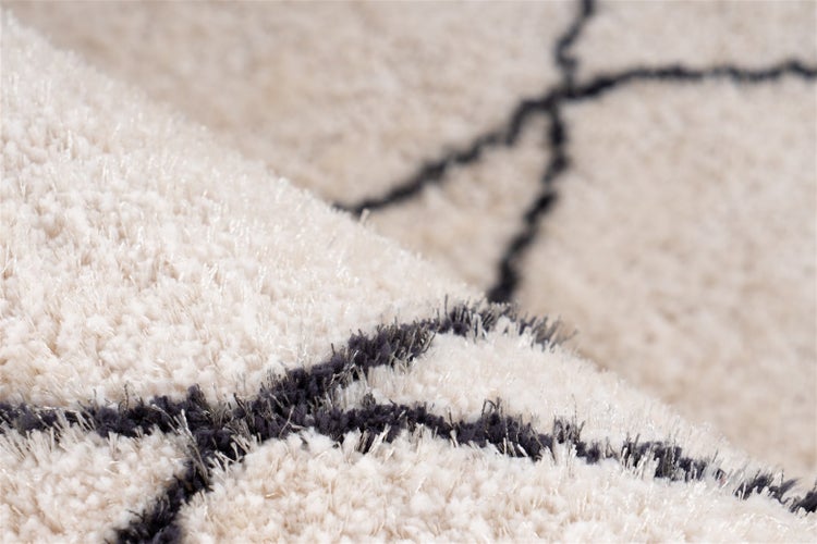 Hochflor-Teppich mit geometrischem Muster in Creme und Dunkelgrau, weiche und dichte Textur.