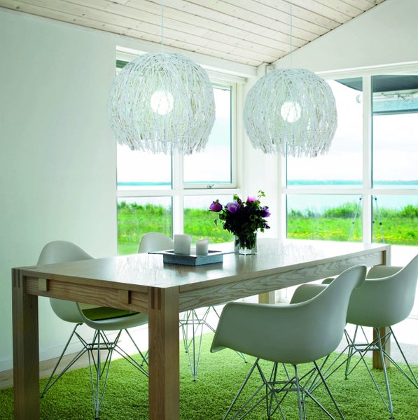 Helle Essecke mit Holztisch, Schalenstühlen und zwei weißen Kugelpendelleuchten.