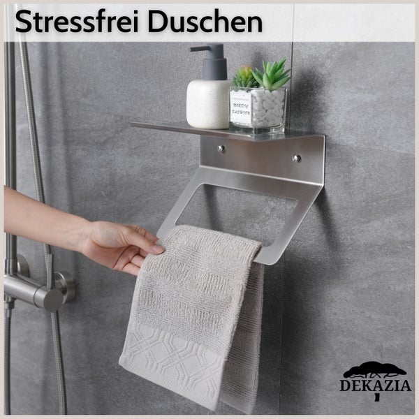 Edelstahl-Badablage mit Handtuchhalter, Seifenspender und kleiner Pflanze an einer Fliesenwand mit einem Handtuch. Dekazia Logo.