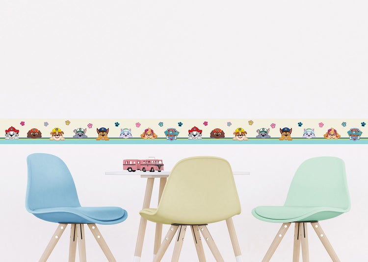Kinderzimmer mit Paw Patrol Tapetenbordüre über einem Tisch mit Spielzeug und drei bunten Stühlen.