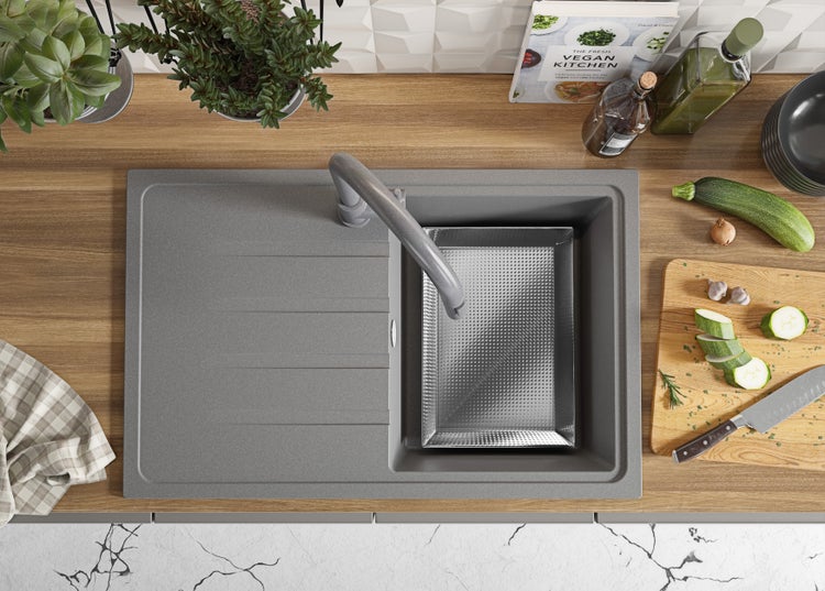 Küchenspüle mit Abtropfbecken, Spültischarmatur und Gemüseschneidebrett auf einer Arbeitsplatte.