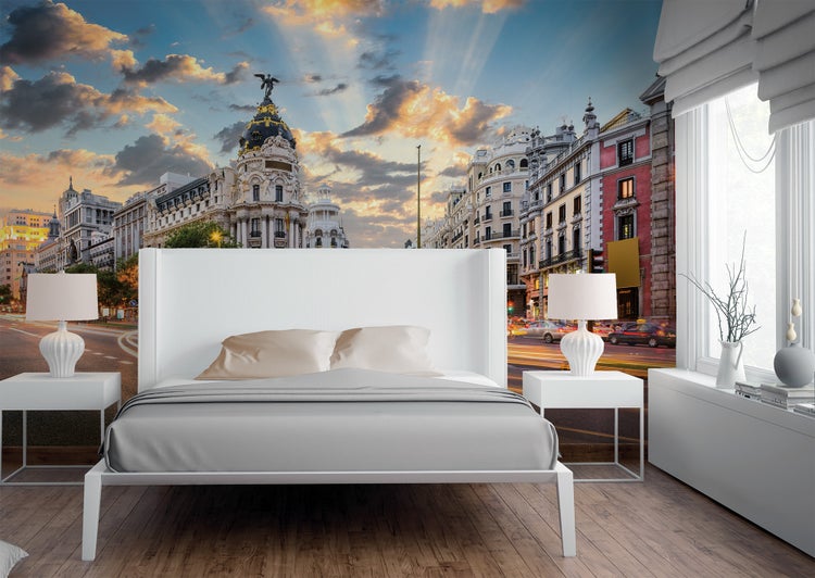 Vlies-Fototapete mit Stadtansicht von Madrid bei Sonnenuntergang in einem Schlafzimmer mit weißem Bett und Parkettboden.