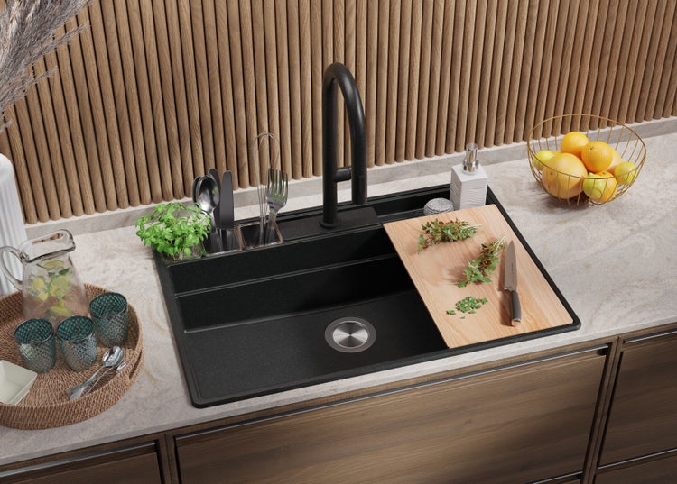 Schwarze Küchenspüle mit Armatur, Schneidebrett und Küchenutensilien auf einer Küchenarbeitsplatte