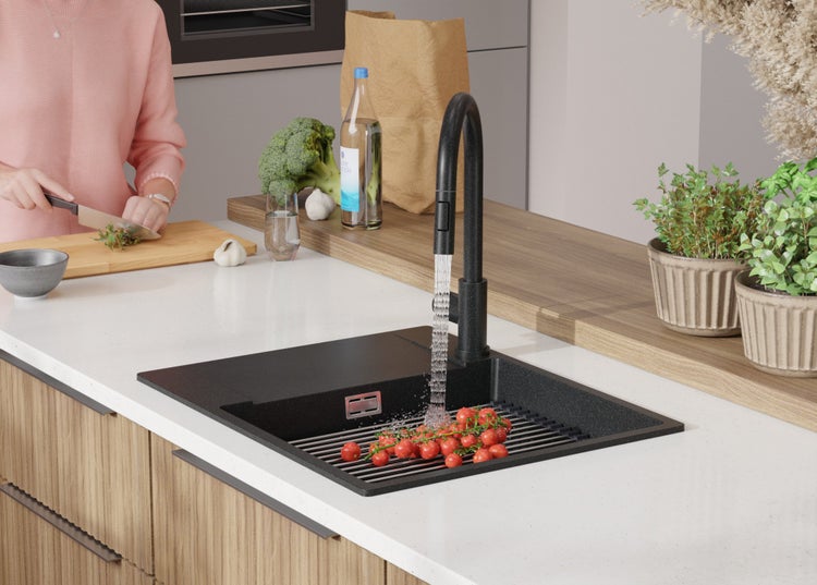 Moderne Küche mit schwarzer Spüle, Armatur und einer Person, die Gemüse schneidet