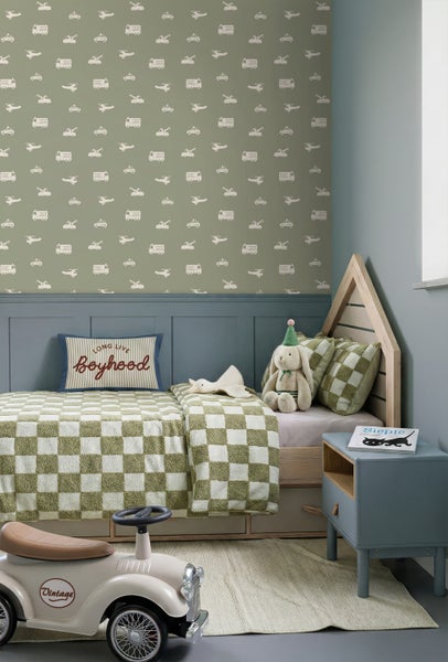 Kinderzimmer mit einer gemusterten Tapete mit Fahrzeugmotiven, einem Hausbett aus Holz, karierter Bettwäsche und einem blauen Nachttisch.