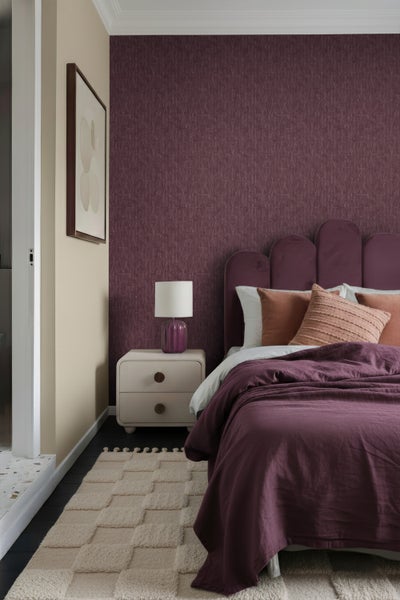 Schlafzimmer mit Bett, Nachttisch, Lampe, Teppich und gemusterter Tapete