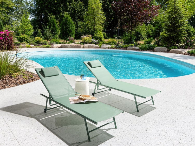 Szene mit zwei Liegestühlen aus Textilgewebe am Pool in einem Garten.