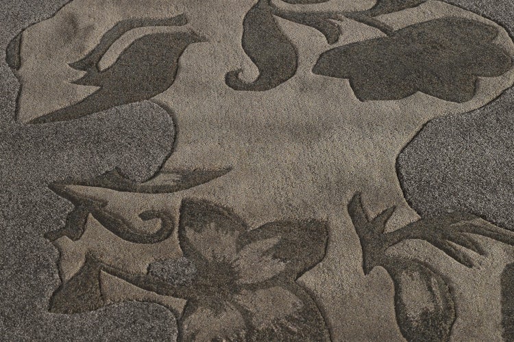 Teppichoberfläche mit eingewebtem floralem Muster und fühlbarer Reliefstruktur durch variierende Florhöhe.