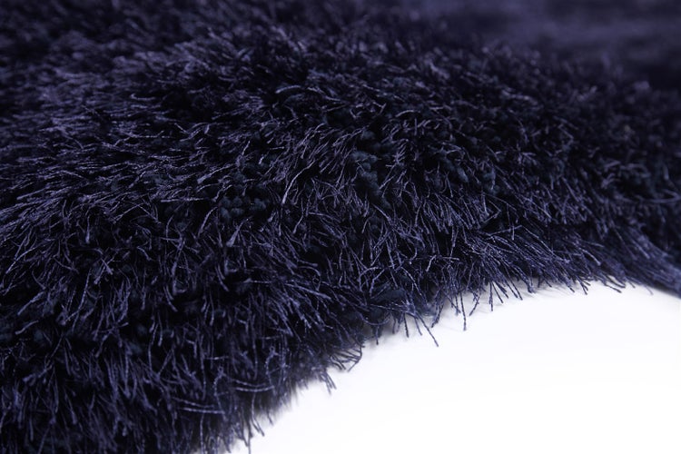 Nahaufnahme eines dunkelblauen Hochflor-Teppichs mit langen, weichen Fasern.