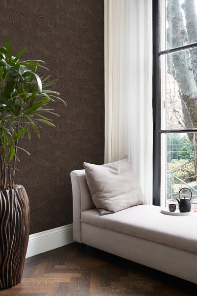 Innenraum mit gemusterter Tapete, Tagesbett am Fenster und Zimmerpflanze