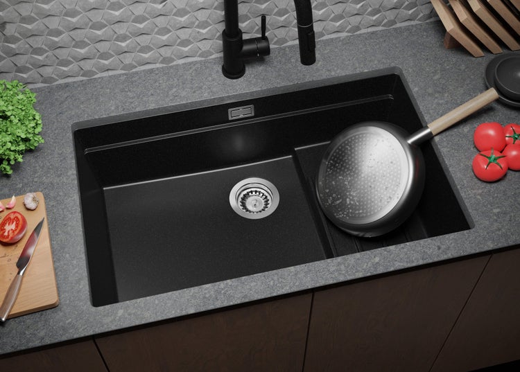 Schwarzes Spülbecken mit Armatur und Küchenutensilien auf einer Arbeitsplatte.
