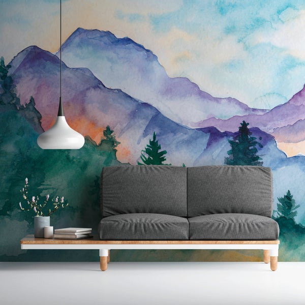 Fototapete mit Aquarell-Berglandschaft und Wald hinter einem grauen Sofa in einem modern gestalteten Wohnzimmer.