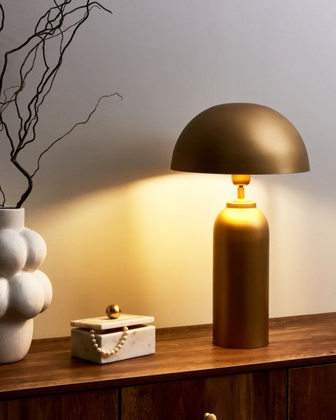 Dekorative Szene mit einer goldenen Tischlampe, einer Blumenvase und einer Schmuckschatulle auf einer Holzkommode.