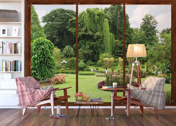 Wohnzimmer mit Sessel und Blick auf einen Garten durch ein großes Fenster