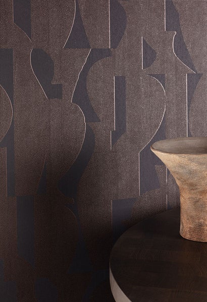 Nahaufnahme einer gemusterten Tapete mit geometrischen Formen und einer Vase auf einem Tisch.
