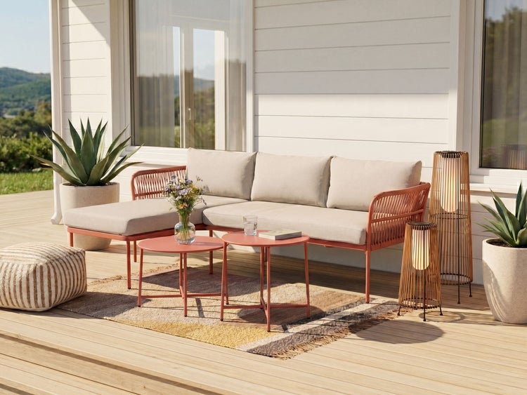 Moderne Gartenlounge auf einer sonnigen Holzterrasse mit einem terracottafarbenen Ecksofa, zwei Couchtischen, Stehlampen und einem Outdoor-Teppich.