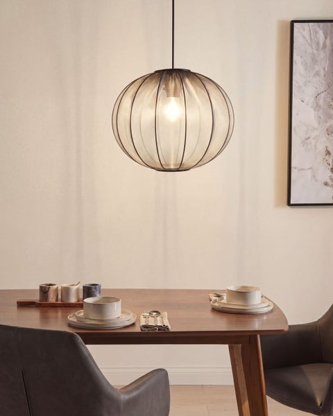 Runde Pendelleuchte mit Metallgeflecht-Schirm über einem hölzernen Esstisch in einem hellen, modern eingerichteten Esszimmer.