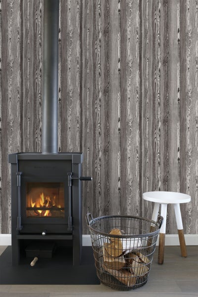 Wohnzimmer mit Kaminofen, Holzkorb und Holztapete