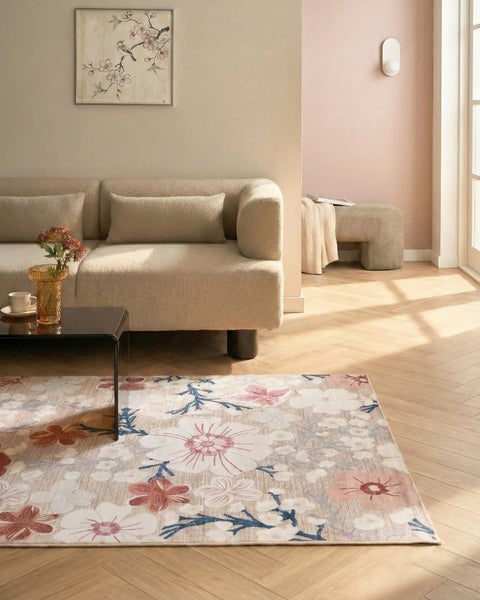 Rechteckiger Teppich mit dichtem floralem Muster aus verschiedenen Blüten in Beige, Altrosa und Terrakotta.