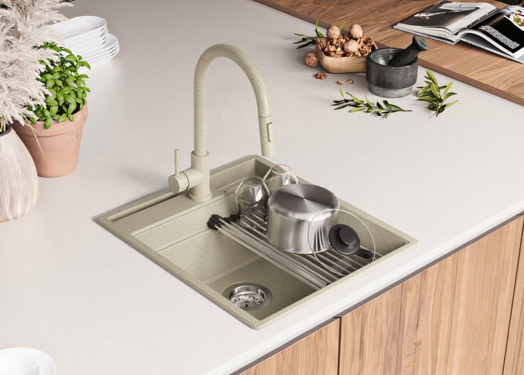 Spüle mit Abtropffläche, Wasserhahn, Geschirr und Küchenutensilien auf einer Küchentheke.