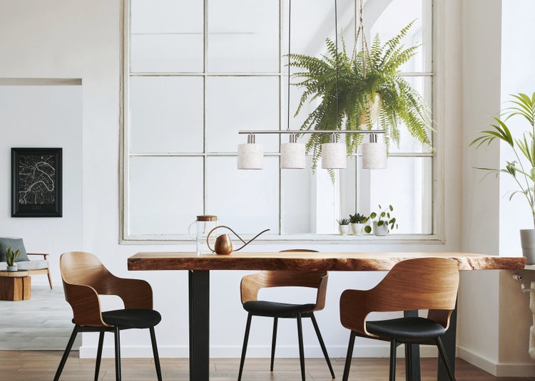 Helles Esszimmer mit Holztisch, Stühlen mit Holzlehnen und Stoffbezug, Hängelampe und Zimmerpflanzen