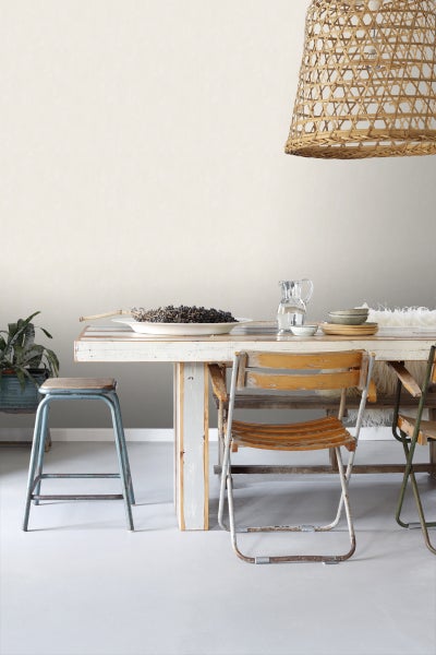 Helles Esszimmer mit Holztisch, Stühlen, Hocker und geflochtener Lampe
